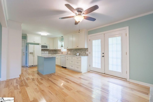 kitchen with french doors, white appliances, white cabinetry, and a kitchen island