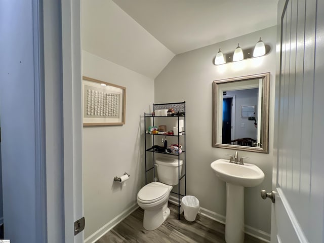 bathroom with wood-type flooring, toilet, lofted ceiling, and sink