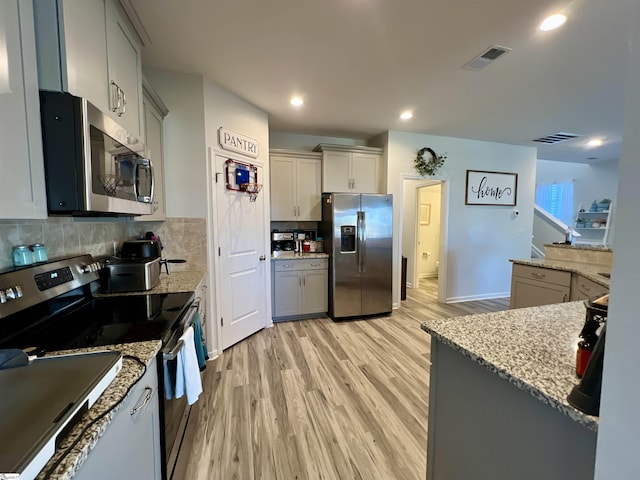 kitchen with gray cabinets, decorative backsplash, light hardwood / wood-style flooring, and appliances with stainless steel finishes