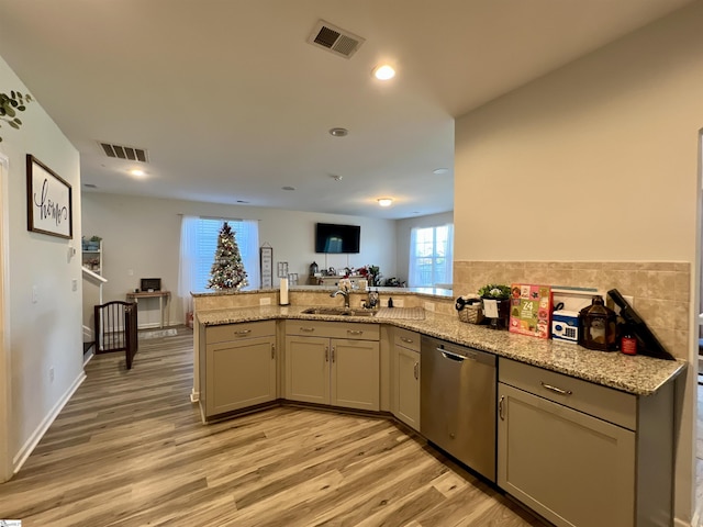 kitchen with sink, stainless steel dishwasher, light wood-type flooring, light stone counters, and kitchen peninsula