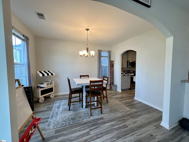 dining room with dark hardwood / wood-style flooring and an inviting chandelier