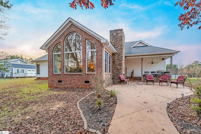 back house at dusk featuring a patio and ceiling fan