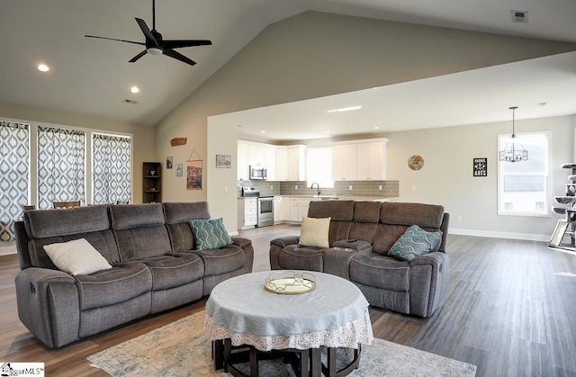 living room with ceiling fan, high vaulted ceiling, and dark wood-type flooring