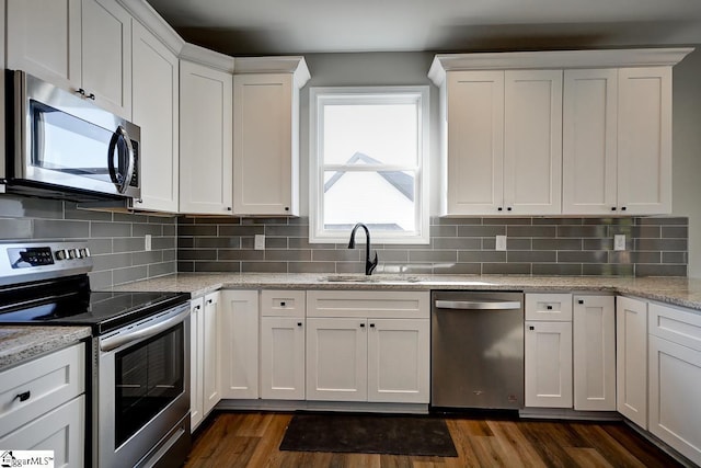 kitchen with stainless steel appliances, white cabinetry, dark hardwood / wood-style floors, and light stone counters