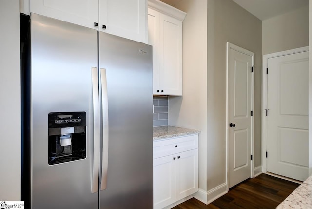 kitchen with decorative backsplash, stainless steel fridge, light stone counters, dark hardwood / wood-style floors, and white cabinetry