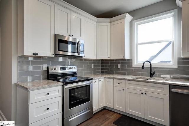 kitchen with light stone countertops, a healthy amount of sunlight, white cabinets, and stainless steel appliances