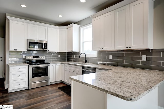 kitchen featuring sink, dark wood-type flooring, light stone counters, white cabinets, and appliances with stainless steel finishes