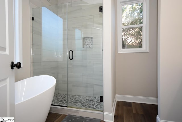 full bathroom featuring baseboards, a freestanding bath, wood finished floors, and a shower stall