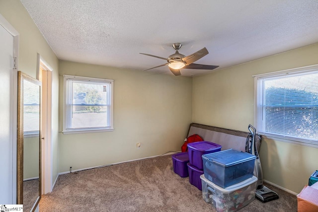 interior space featuring a textured ceiling, carpet floors, and ceiling fan