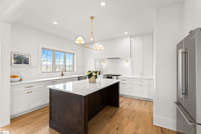 kitchen featuring pendant lighting, light hardwood / wood-style floors, white cabinetry, and stainless steel appliances