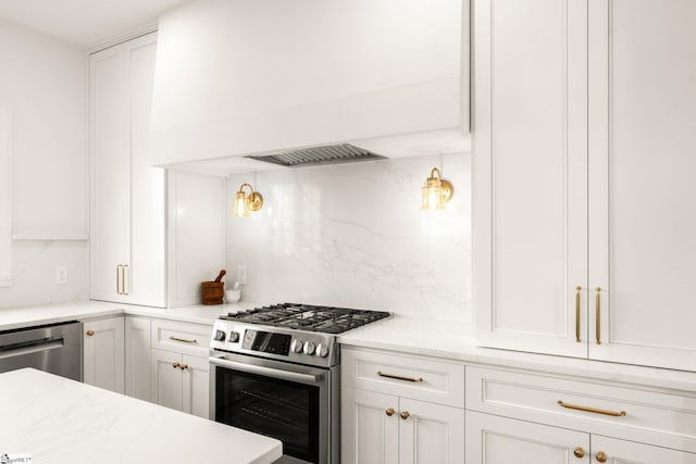 kitchen featuring white cabinets, appliances with stainless steel finishes, tasteful backsplash, and light stone countertops