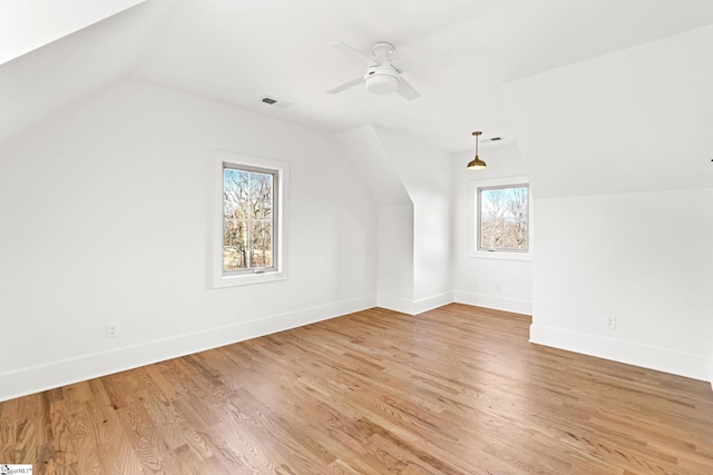 additional living space featuring light wood-type flooring, a wealth of natural light, lofted ceiling, and ceiling fan