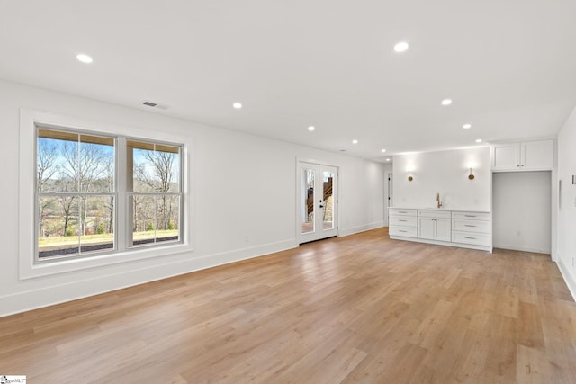 unfurnished living room with french doors and light hardwood / wood-style floors