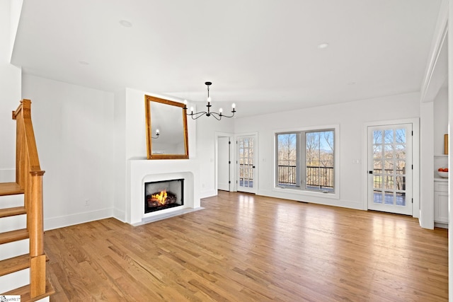 unfurnished living room featuring light hardwood / wood-style flooring and a notable chandelier