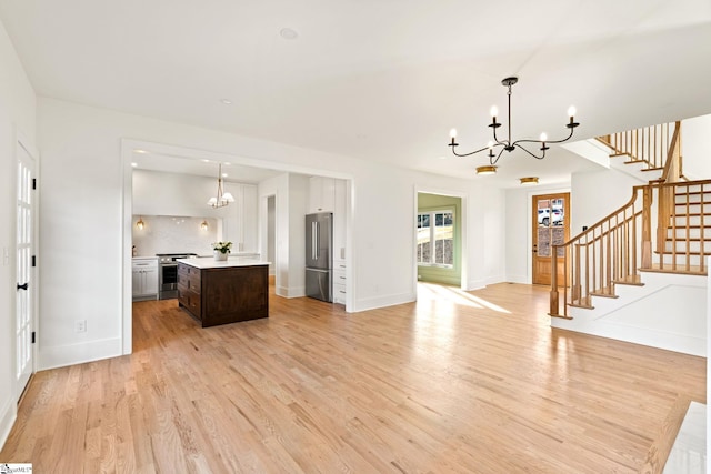 kitchen featuring decorative backsplash, appliances with stainless steel finishes, dark brown cabinets, pendant lighting, and light hardwood / wood-style flooring