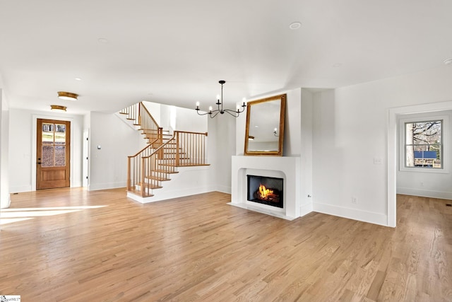 unfurnished living room featuring light wood-type flooring and a notable chandelier