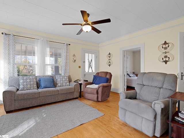 living room featuring ceiling fan, plenty of natural light, wood-type flooring, and ornamental molding