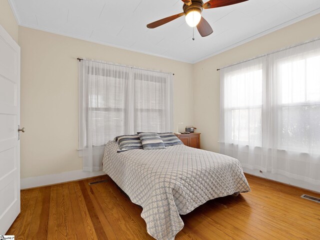 bedroom with wood-type flooring, ceiling fan, and ornamental molding