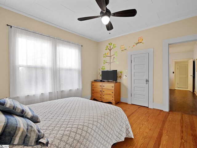 bedroom with ceiling fan, crown molding, and wood-type flooring