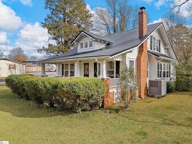 exterior space featuring central air condition unit, a front lawn, and covered porch