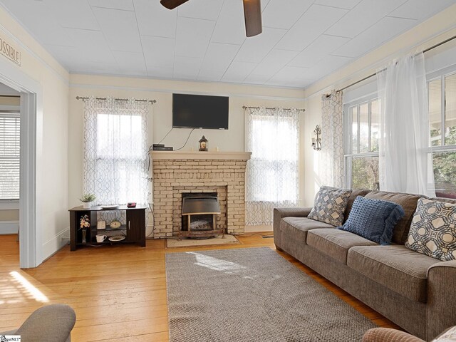 living room featuring a fireplace, wood-type flooring, and a wealth of natural light