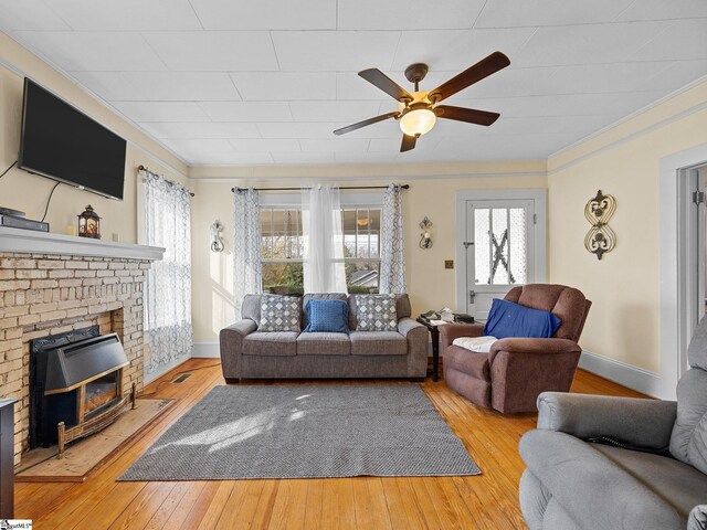 living room featuring a wood stove, crown molding, light hardwood / wood-style flooring, and ceiling fan