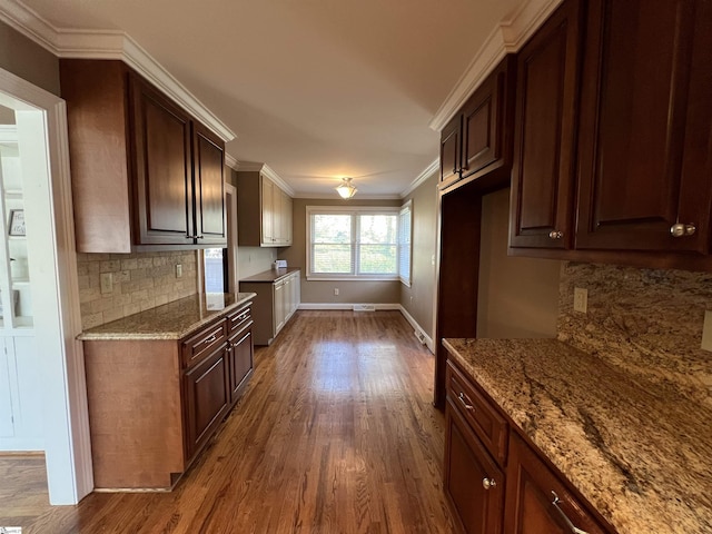 kitchen with tasteful backsplash, light stone counters, dark hardwood / wood-style floors, crown molding, and dark brown cabinets