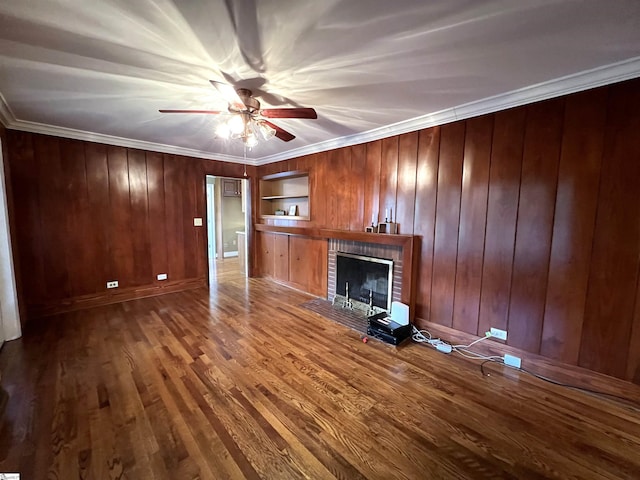 unfurnished living room with a fireplace, hardwood / wood-style flooring, crown molding, and wood walls