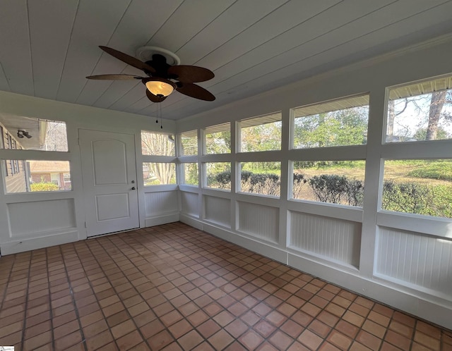 unfurnished sunroom featuring ceiling fan and a healthy amount of sunlight