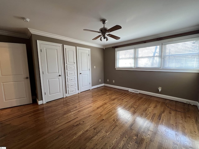 unfurnished bedroom featuring two closets, dark hardwood / wood-style floors, ceiling fan, and ornamental molding