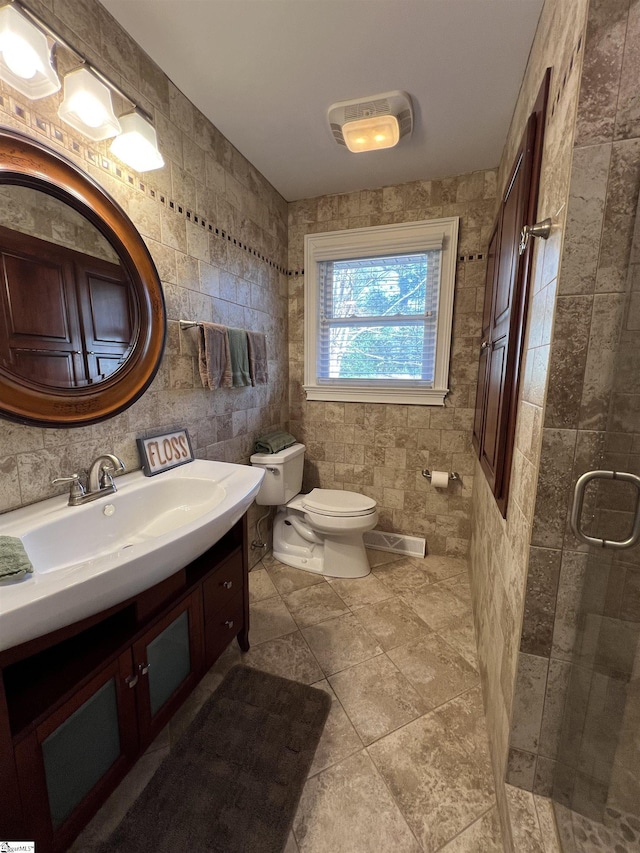 bathroom featuring a shower with door, vanity, tile walls, and toilet