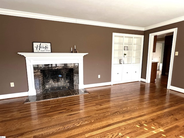 unfurnished living room with hardwood / wood-style flooring, built in shelves, a premium fireplace, and ornamental molding