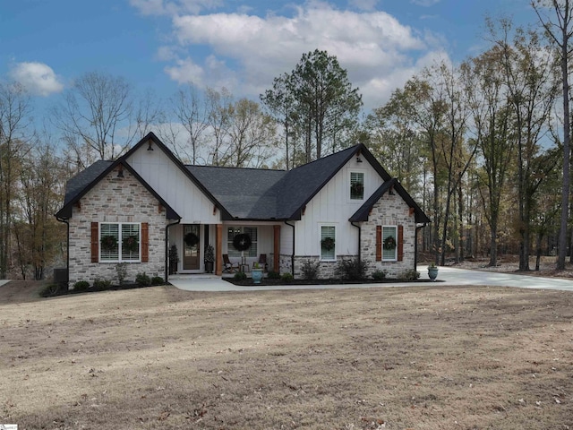 modern farmhouse with stone siding, a shingled roof, and board and batten siding