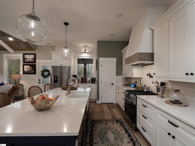 kitchen with dark hardwood / wood-style flooring, custom exhaust hood, stainless steel appliances, sink, and hanging light fixtures