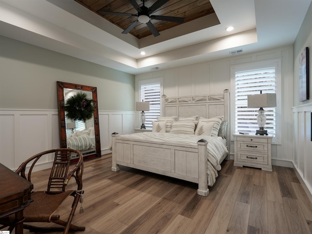 bedroom with a raised ceiling, ceiling fan, and wood-type flooring