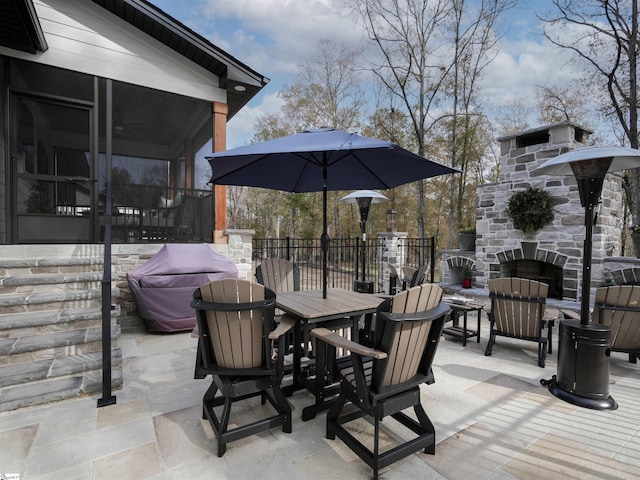 view of patio / terrace with an outdoor stone fireplace and a sunroom