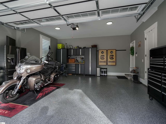 garage with stainless steel fridge and a garage door opener