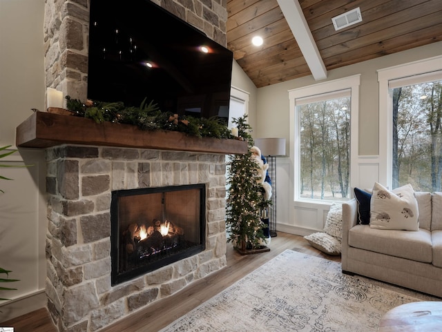 living room with lofted ceiling with beams, light hardwood / wood-style floors, wood ceiling, and a fireplace