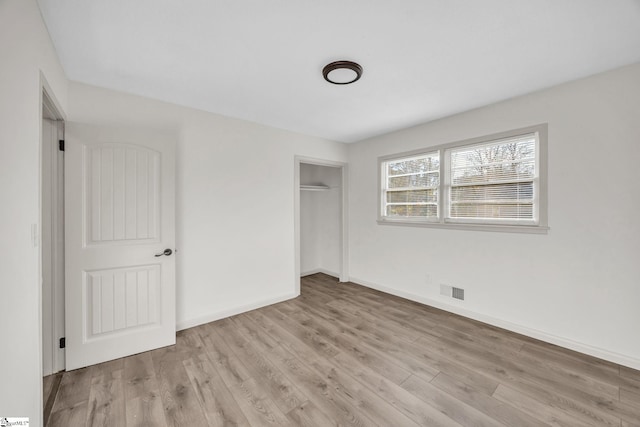 unfurnished bedroom with light wood-type flooring and a closet