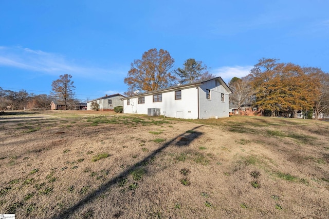 view of side of home with a lawn and central air condition unit