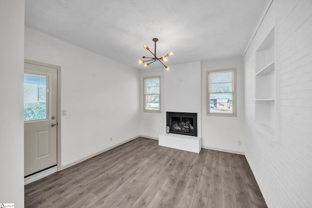 unfurnished living room featuring hardwood / wood-style flooring, a large fireplace, and a chandelier