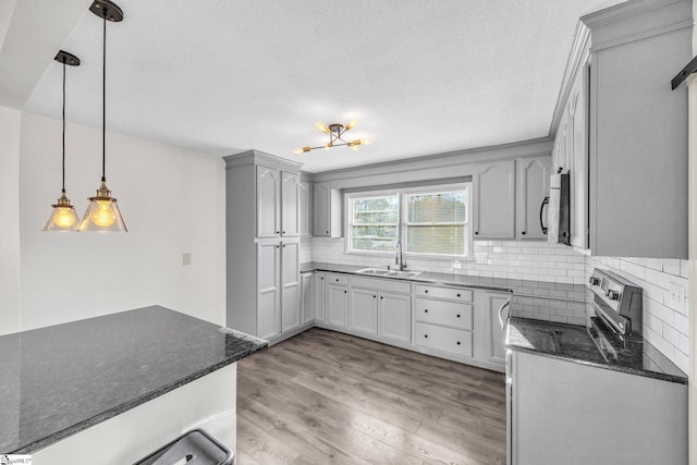 kitchen featuring decorative backsplash, gray cabinetry, sink, decorative light fixtures, and light hardwood / wood-style floors