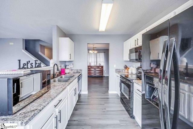 kitchen with hardwood / wood-style floors, black appliances, sink, a textured ceiling, and white cabinetry