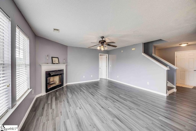 unfurnished living room with hardwood / wood-style floors, ceiling fan, a textured ceiling, and a wealth of natural light