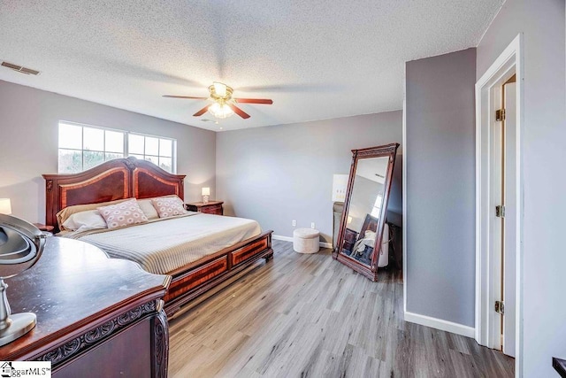 bedroom with ceiling fan, light hardwood / wood-style flooring, and a textured ceiling