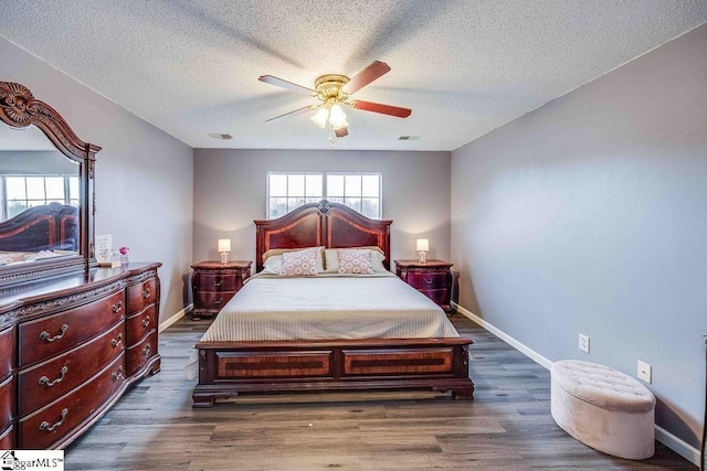 bedroom with a textured ceiling, ceiling fan, and dark wood-type flooring