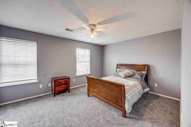 carpeted bedroom with ceiling fan and a textured ceiling