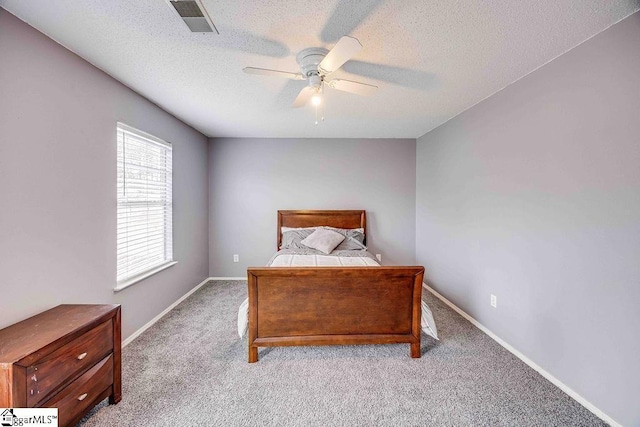 bedroom with ceiling fan, light colored carpet, and a textured ceiling