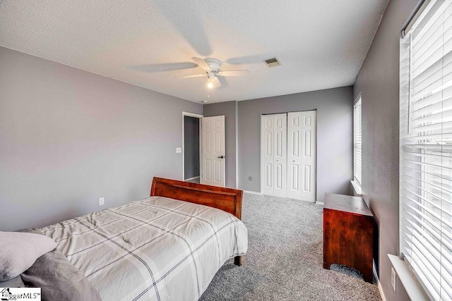 carpeted bedroom with ceiling fan, a textured ceiling, and a closet