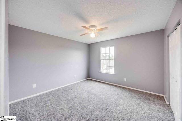 carpeted spare room with ceiling fan and a textured ceiling